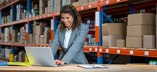 Woman in warehouse typing on computer