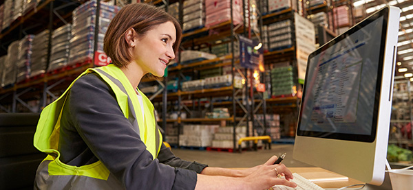 Woman in warehouse typing on computer