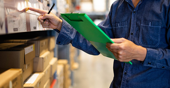 two workers in warehouse looking at a tablet 