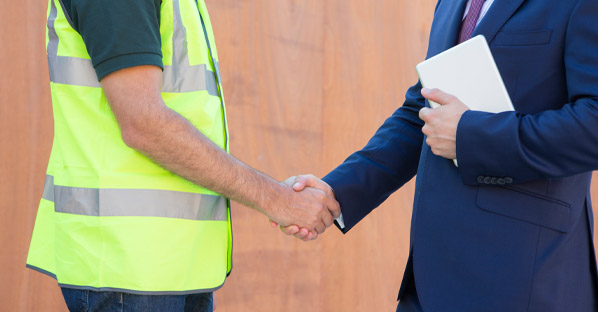 Construction crew member and businessman shaking hands